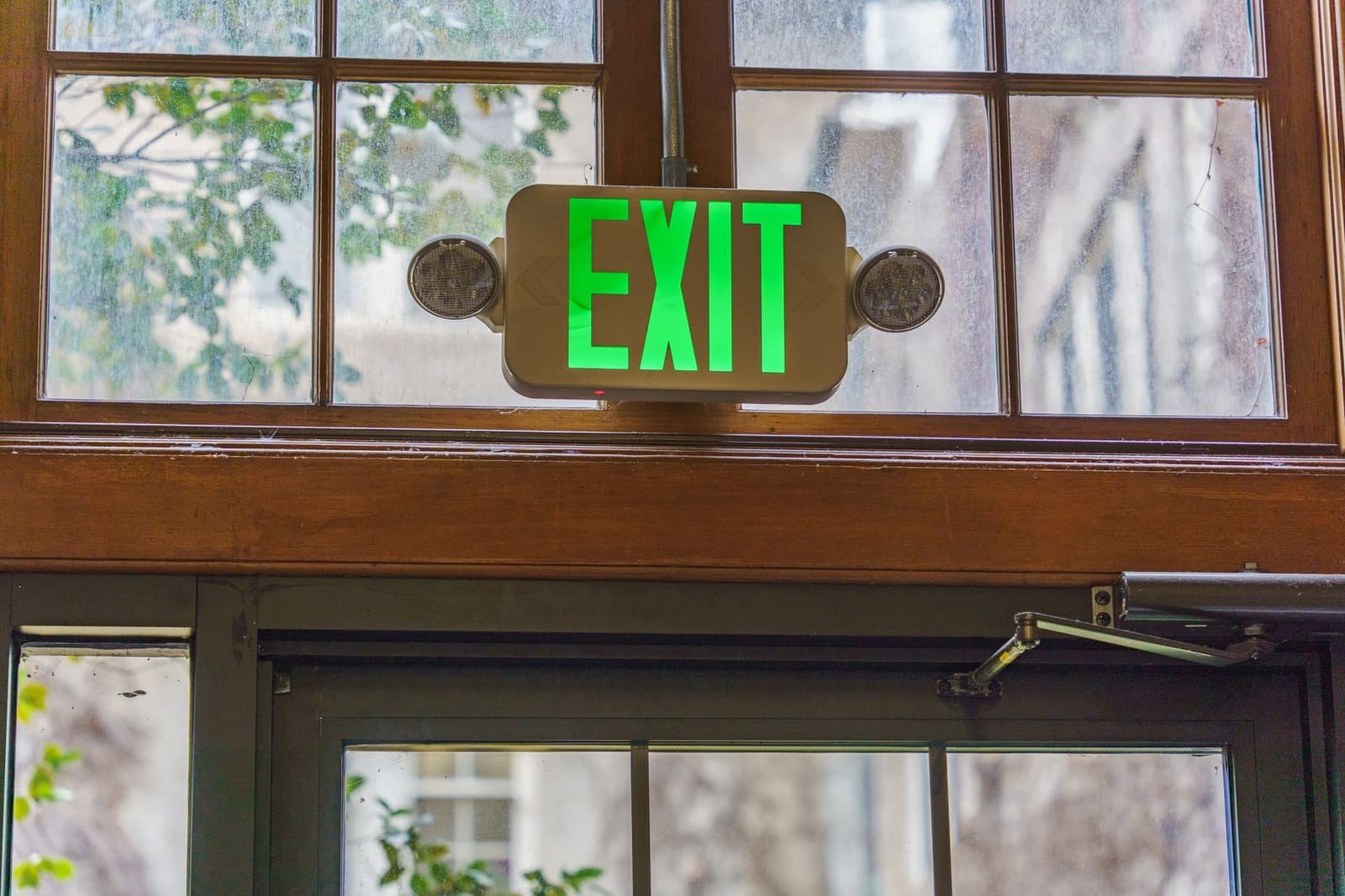 Señalamiento de salida de emergencia iluminado sobre puerta interior