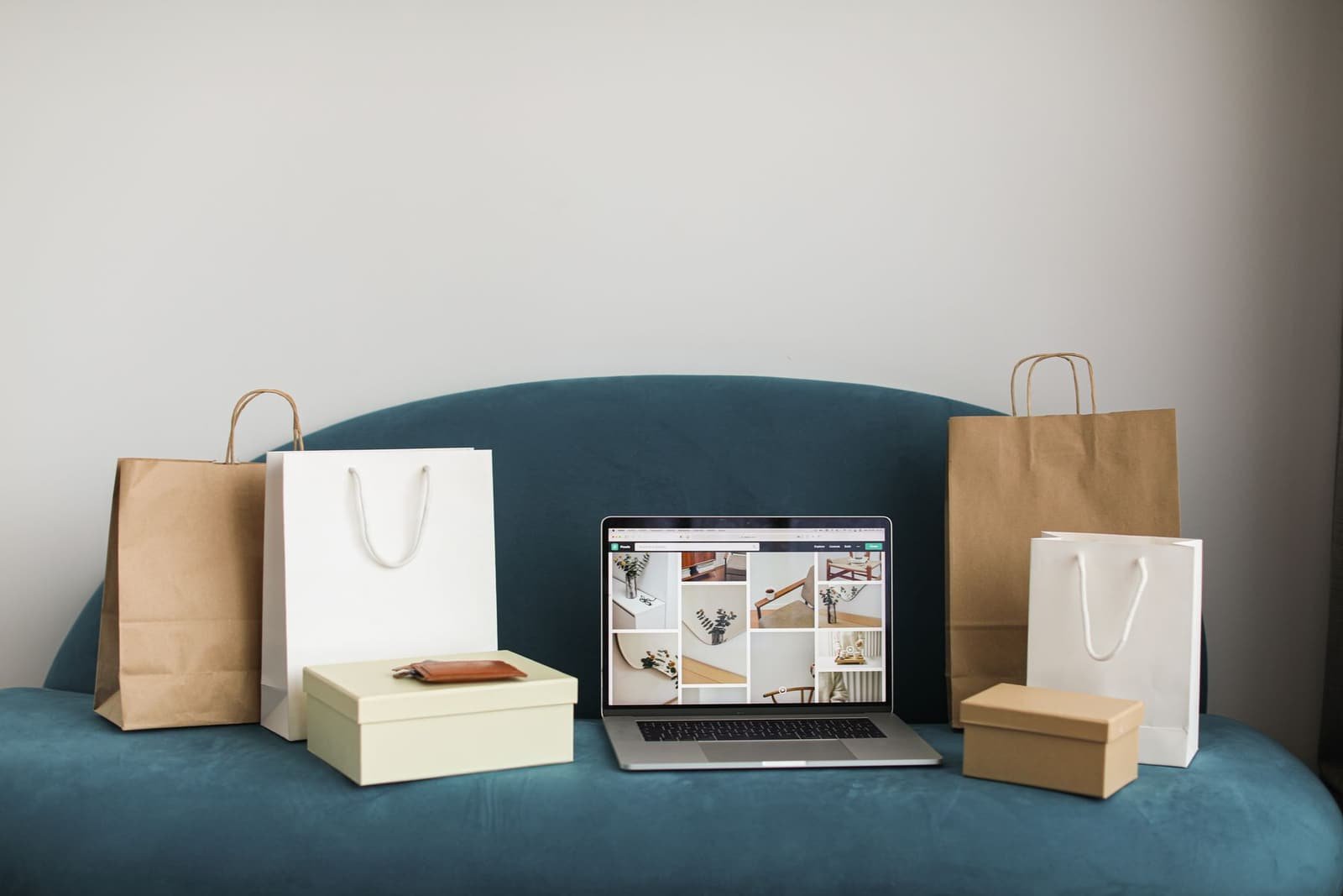 Laptop con un catálogo de productos en pantalla, rodeada de cajas y bolsas de compra